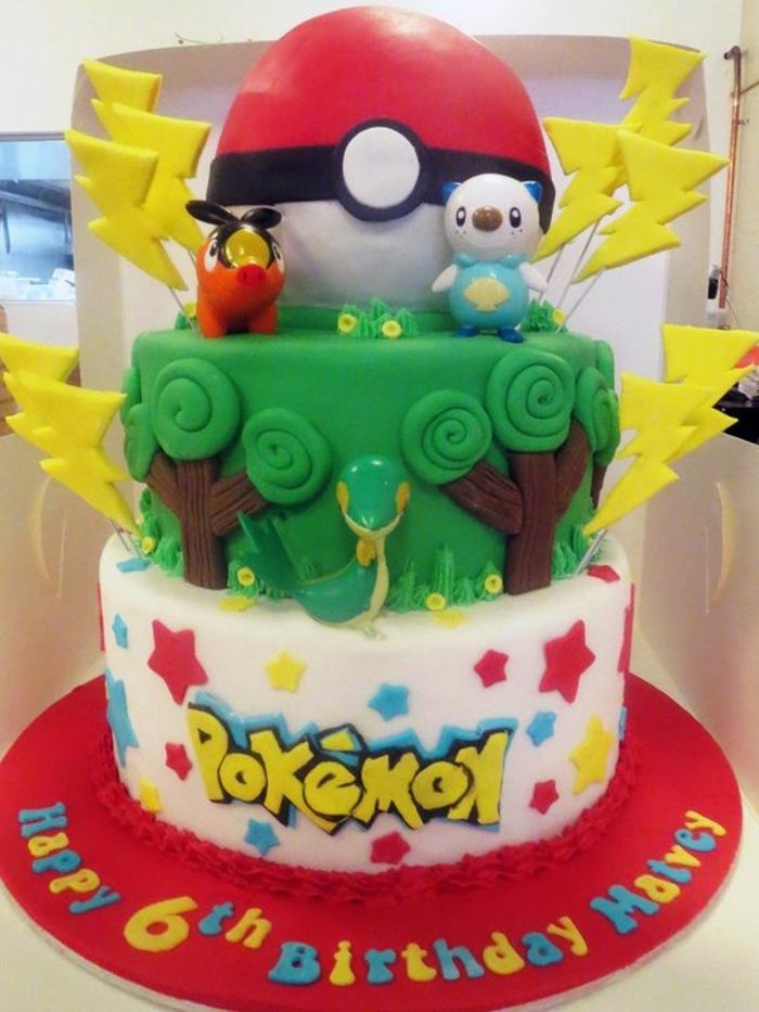 torta pokemon a due livelli con alberi verdi, serpente, lampi gialli e un pokeball rosso