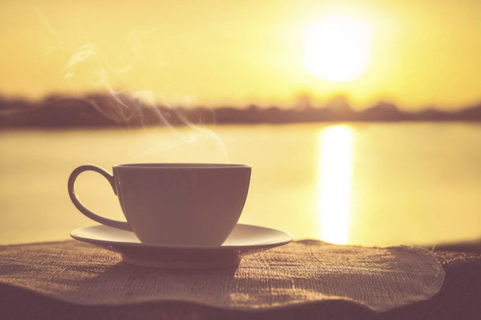 Imagini buni dimineata - o ceașcă de cafea cu abur în fundalul răsăritului