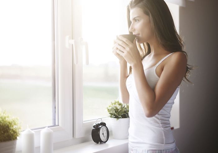 Imagini buni dimineata - o fata se bucura de cafea si se uita prin fereastra