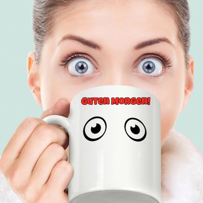 o cană de cafea pictată cu doi ochi mari și o tânără doamnă cu ochi albaștri mari