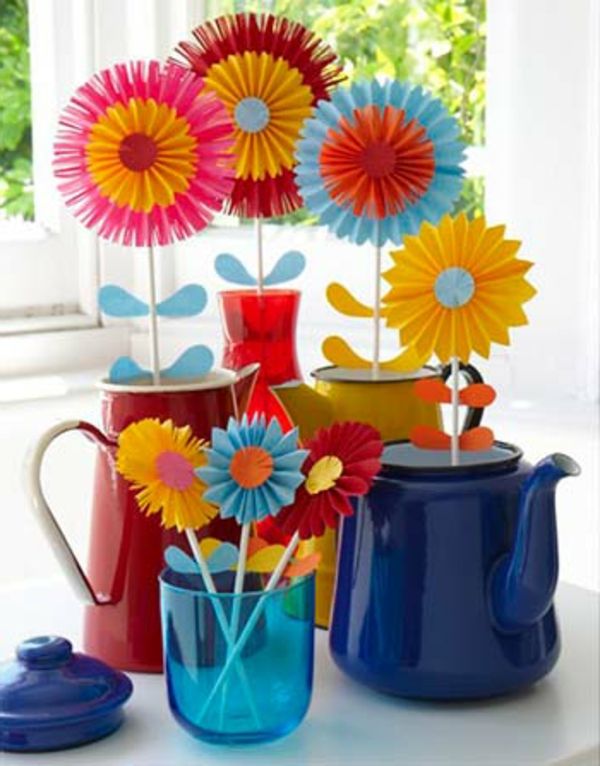 Enkel-håndverk-blomster-fra-fargerik-papir-et stort vindu bak seg
