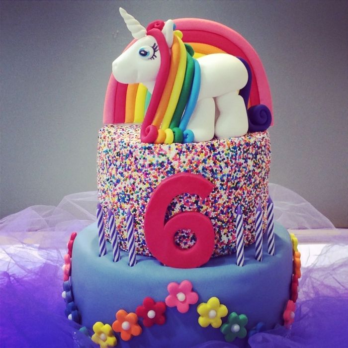 torta de unicórnio - aqui é uma torta com cores e um pequeno unicórnio com juba de cor do arco-íris