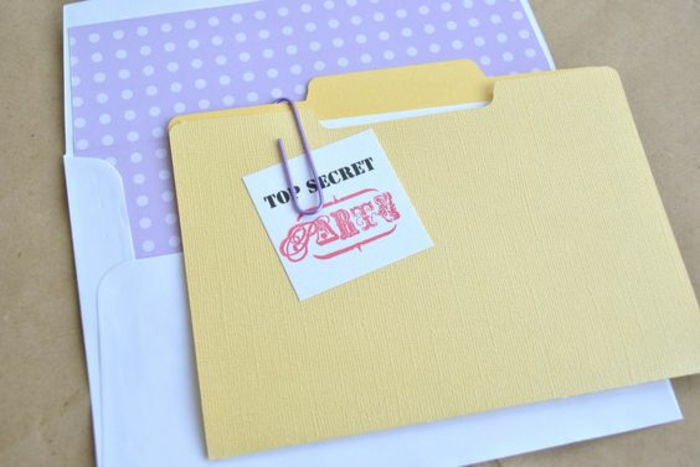 Tinker-uitnodigingskaarten zelf: gele map voor personeelsdossier, witte envelop, notitie, paarse paperclip
