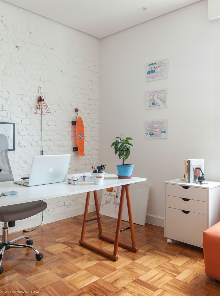 Studiu în alb, birou de scris din lemn, scaun din piele gri cu roți, skateboard pe perete