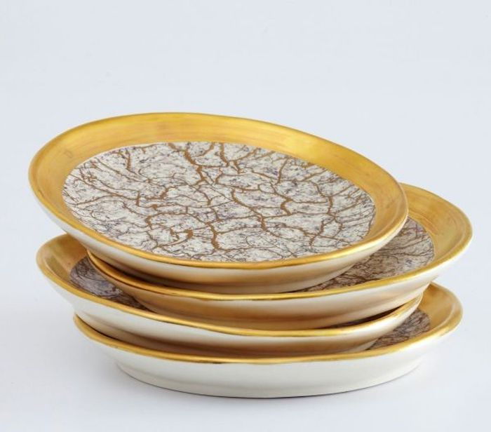 cztery okrągłe talerze ze złoconymi krawędziami i dekoracją w marmurze, zestaw talerzy z czterech talerzy z dekoracjami w kolorze złotym, zdjęcie z biało-szarym tłem