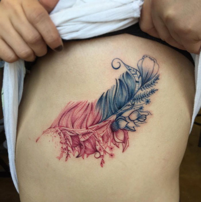 femeie cu tatuaj cu pene pe partea corpului, pene în combinație cu flori