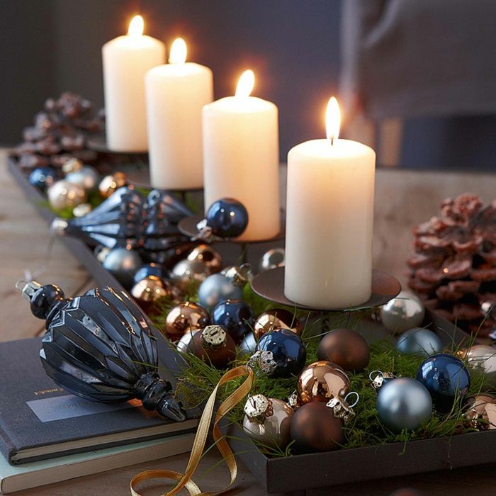 Štyri sviečky na čiernom svietniky vyrobené z nerezovej ocele, malé vianočný strom gule v rôznych farbách s lesklým a matným povlakom, dekoratívny prvok pre vianočný strom z modrej, ľahko rozbitného skla, dve veľké kužele na bohato vyzdobený stôl, dve knihy - jedna s tmavo modrá a jedna s jasne zelenú obálkou