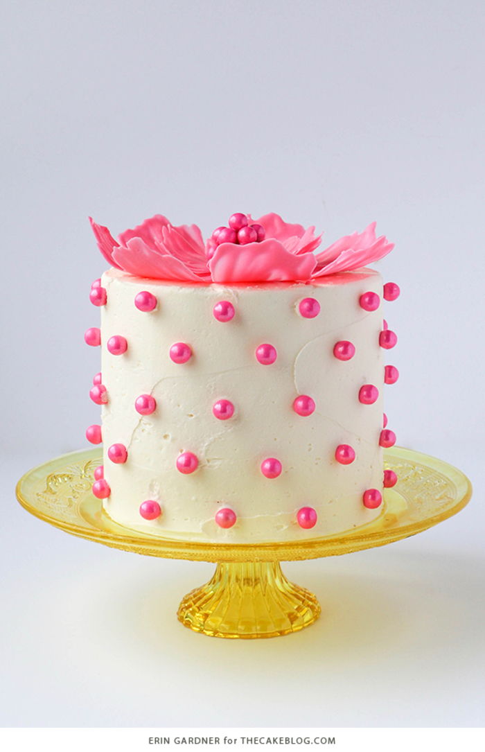 lindo bolo de aniversário, decorado com uma flor rosa e miçangas