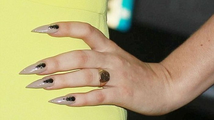 Žebljani nohti Lady Gaga beige barve nohtov črne in zlate obročke rumene obleke
