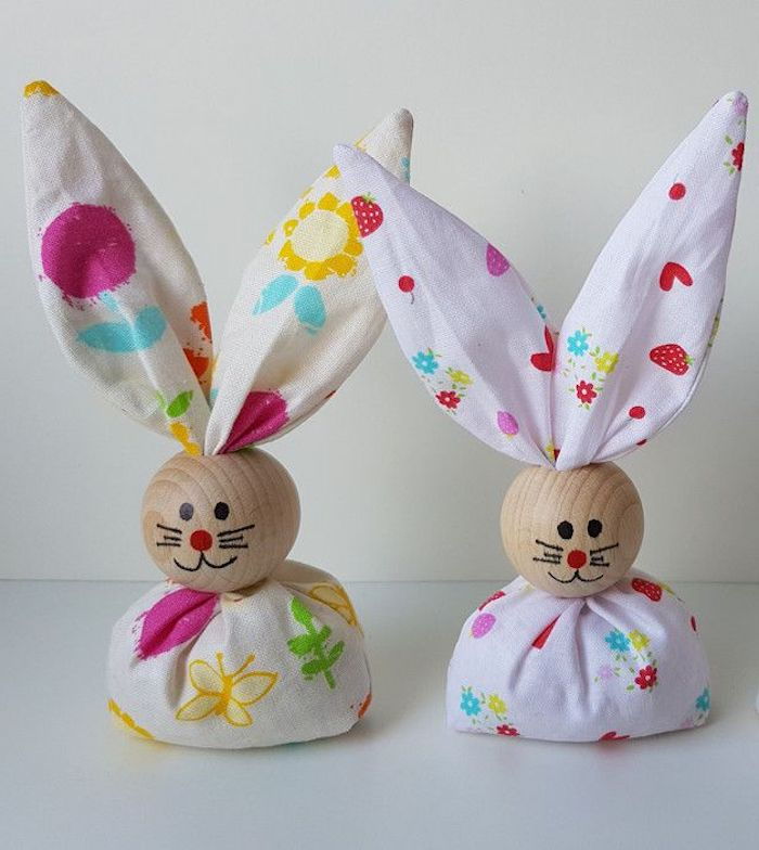 dva malé králiky v bielom tkanive s potlačou, drevené hlavy s maľovanými kĺbmi