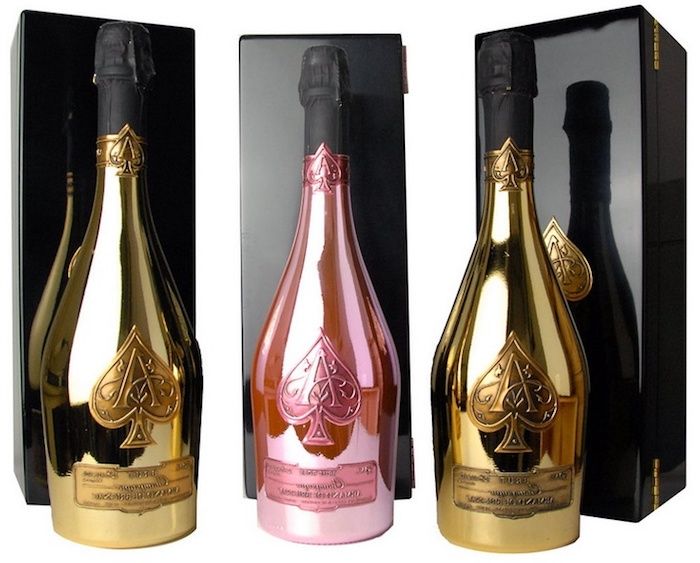 trzy butelki szampana z opakowaniem premium w kolorze złotym i różowym, każdy z łopatą, trzy czarne pudełka na butelki szampana