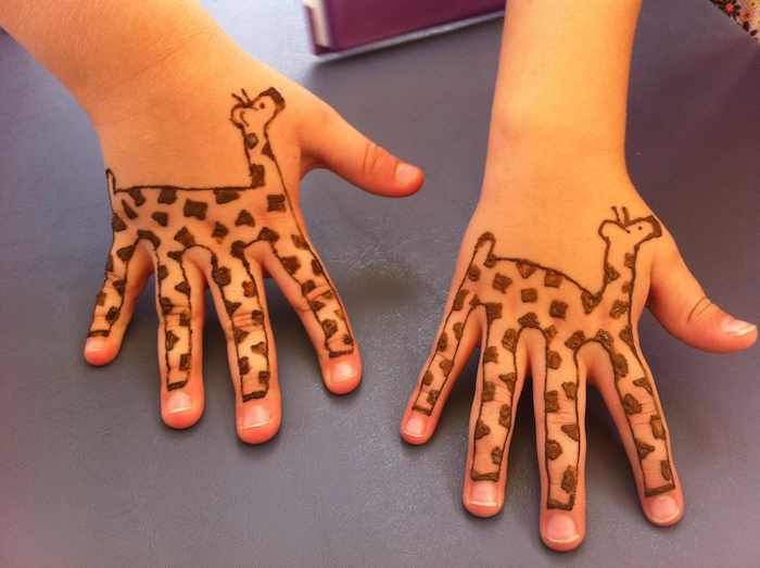 twee kleine zussen met henna-tatoeages van giraffen op kleine handen