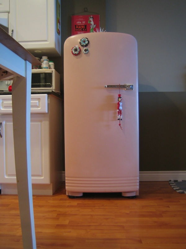 Stort rosa kjøleskap ved siden av en hvit bar