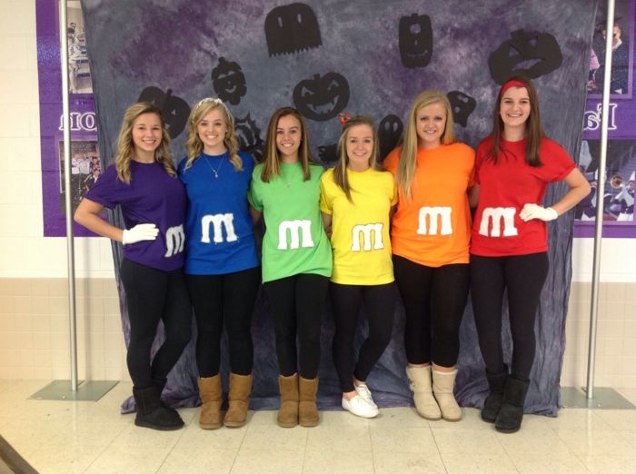 sex söta tjejer presenterar alla färgerna på M M godis - kostymgruppen