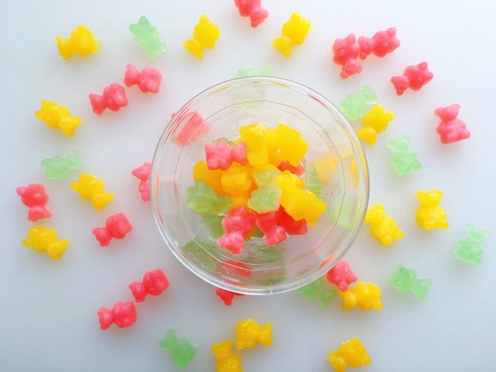 Tre farger av gummi bjørn gjør seg i en bolle med glass og andre sprinklet rundt den