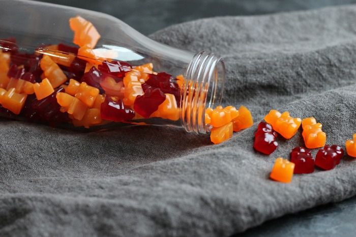 en flaske hjemmelagde gummy bjørner i oransje og rød farge - gjør gummy bears selv