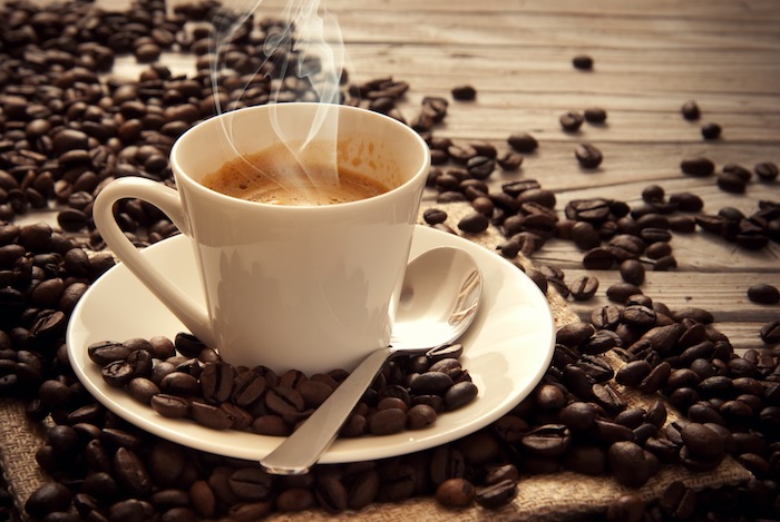 Bună dimineața - cafea cu lapte pe o masă de lemn cu boabe de cafea în jurul ei