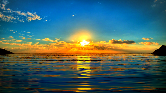 Bună dimineața - un răsărit de soare peste apă cu nori mici