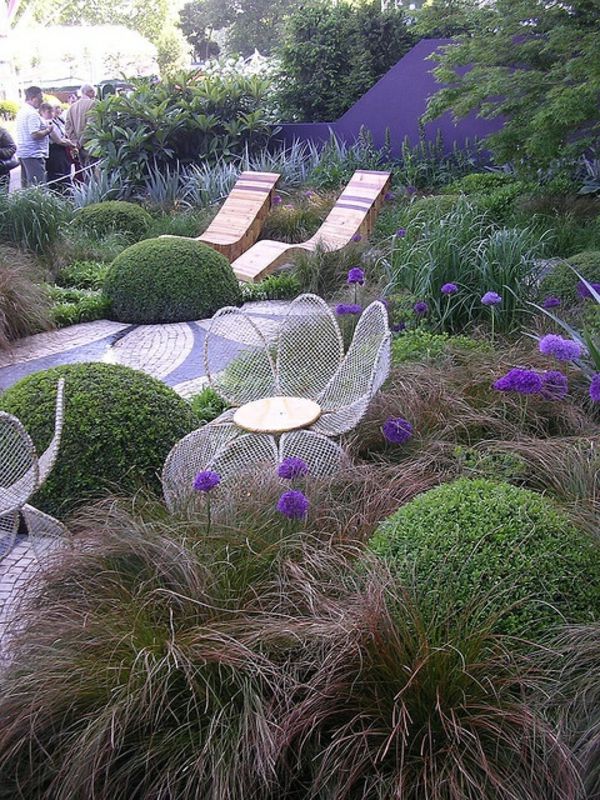 houten ligstoelen in mediterrane tuin met groene planten