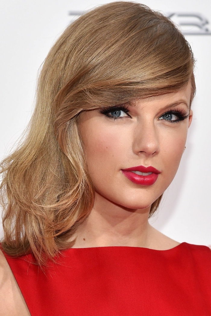 Taylor Swift în păr roșu, brun deschis și ochi albaștri, buze strălucitoare roșii și rouge strălucitoare