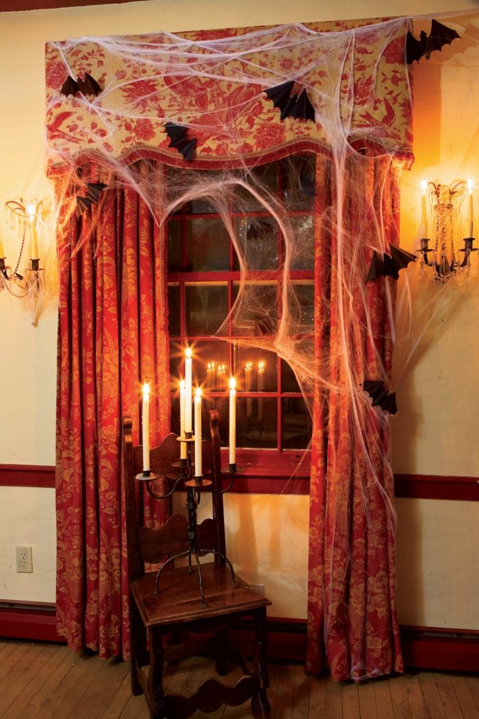 Halloween dekoration, spindelväv och fladdermöss av papper, ljushållare på fönstret