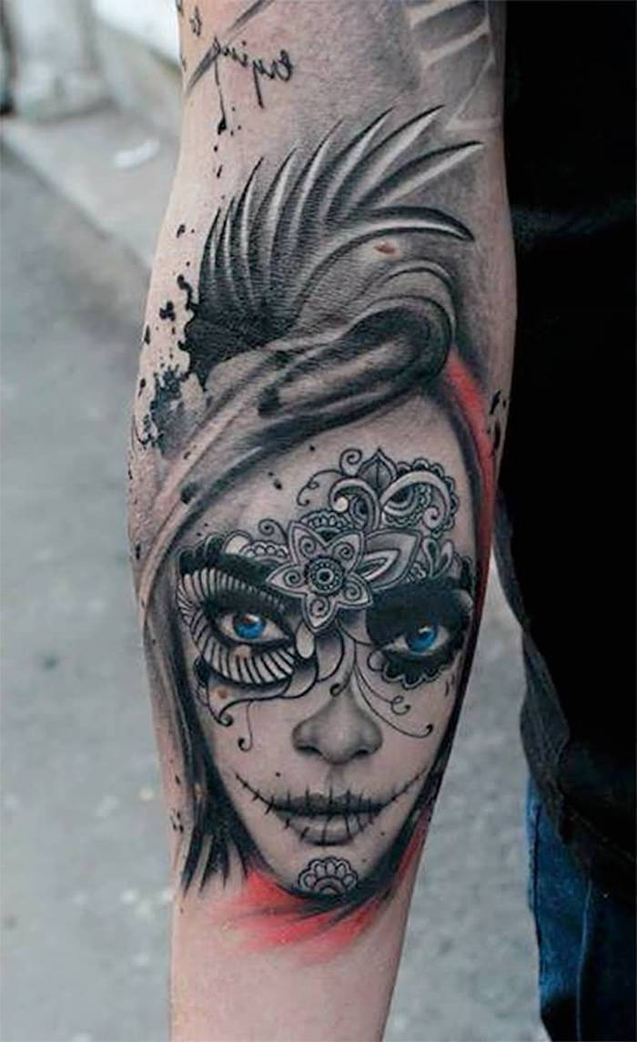 Hand met een tatoeage van een jonge vrouw met blauwe ogen en met witte bloemen en zwarte lippen - La Catrina-tatoeage
