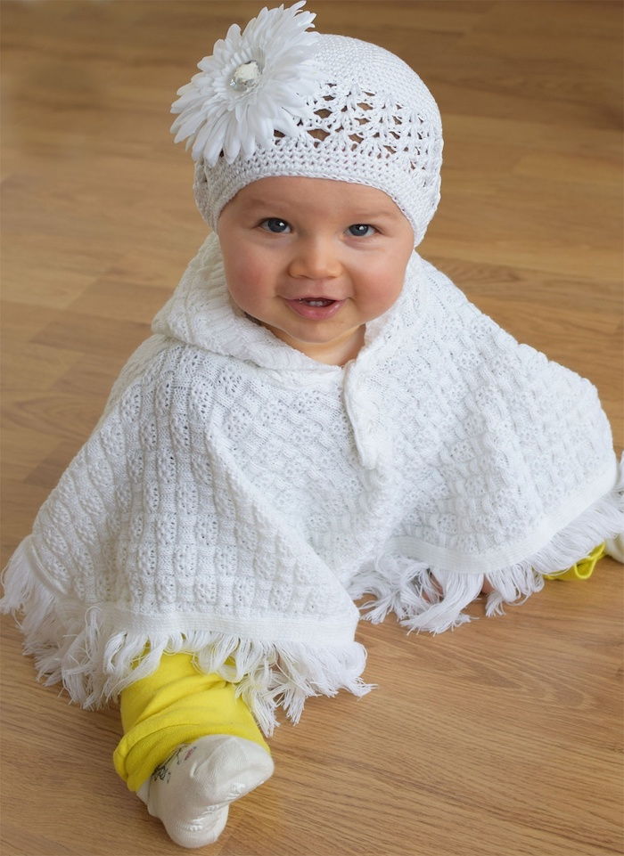 urocza dziewczynka z białym poncho, jak robisz na drutach ponczo dla dziecka