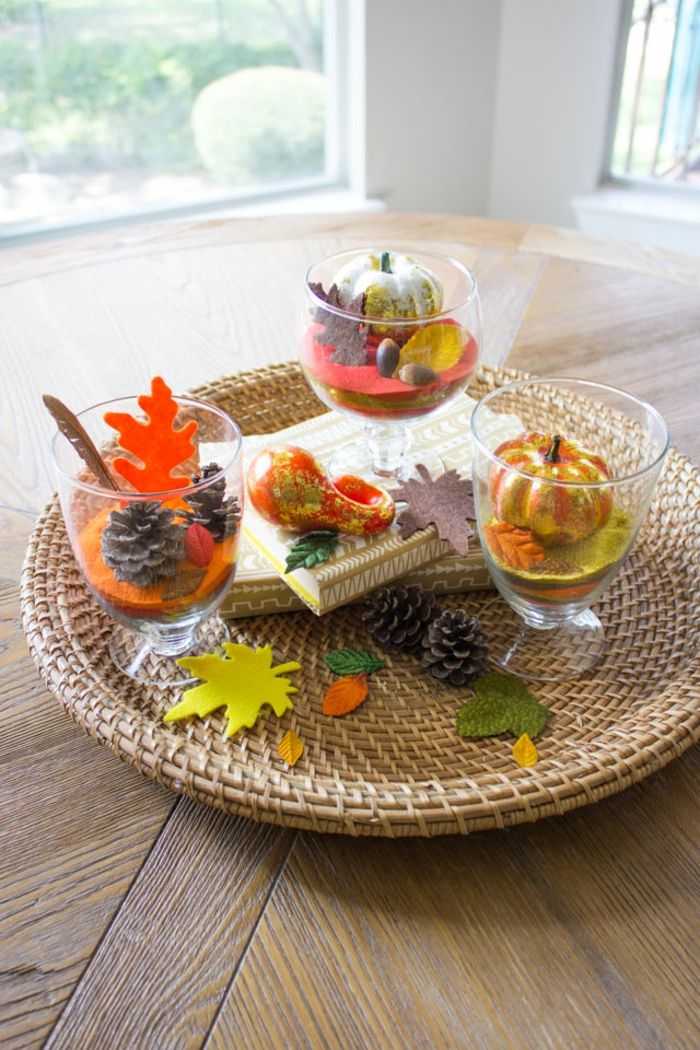 usporiadanie stola jesenne, dosky z ratanu, šišky a malé tekvice v pohároch, jesenné nuansy