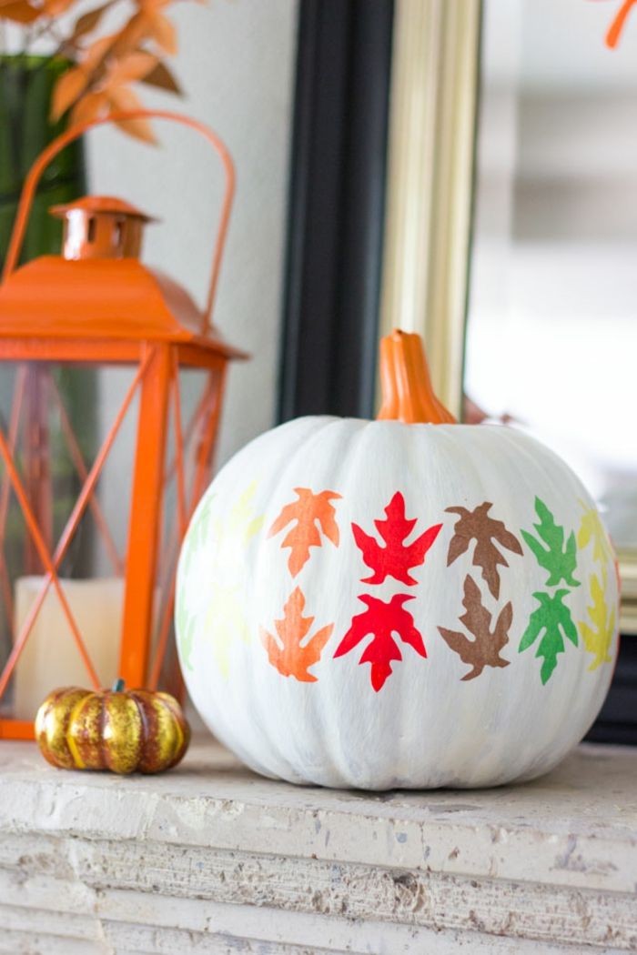 Jesienna dekoracja na zewnątrz, dynie malowane i ozdobione kolorowymi liśćmi, proste i skuteczne