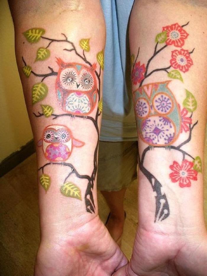 doua maini cu tatuaje colorate de poveste cu bufnite si uhu si un copac cu frunze verzi