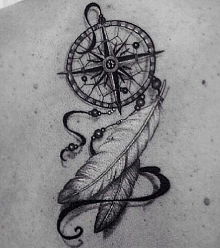 Czarny tatuaż z małym czarnym kompasem i dwoma pięknymi białymi długimi piórami