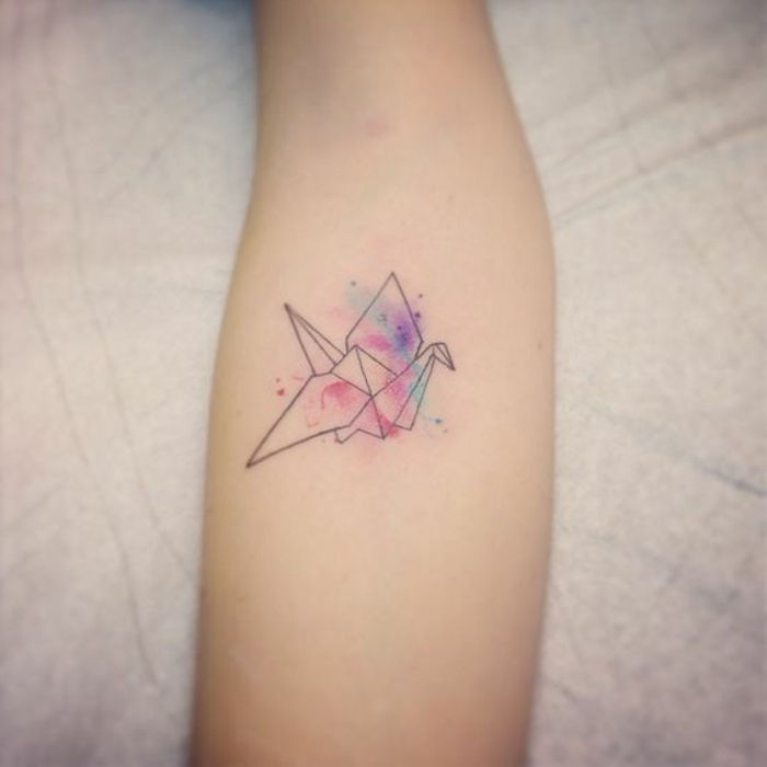 questa è un'idea sul tema del tatuaggio origami - una mano con un piccolo tatuaggio origami colorato - un uccello volante colorato