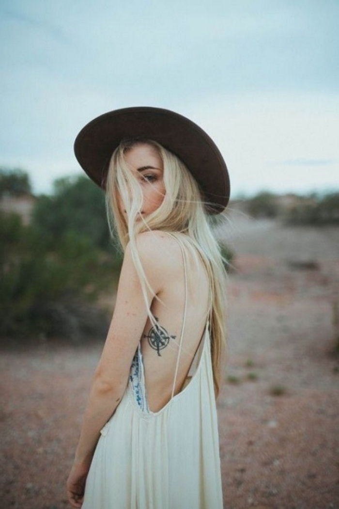 Młoda kobieta w czarnym kapeluszu iz małym eleganckim tatuażem z czarnym kompasem