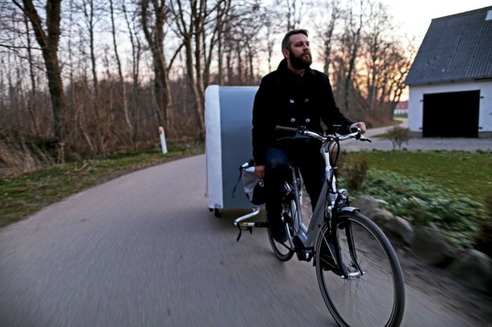 un ciclista con un cappotto nero e una bicicletta con una roulotte per biciclette