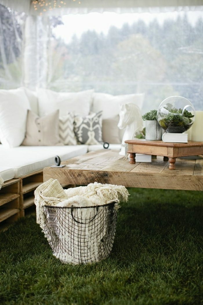 een tafel en een bank gemaakt van oude paletten met kleine witte kussens en een terarrium - idee om zelf palletmeubelen te bouwen