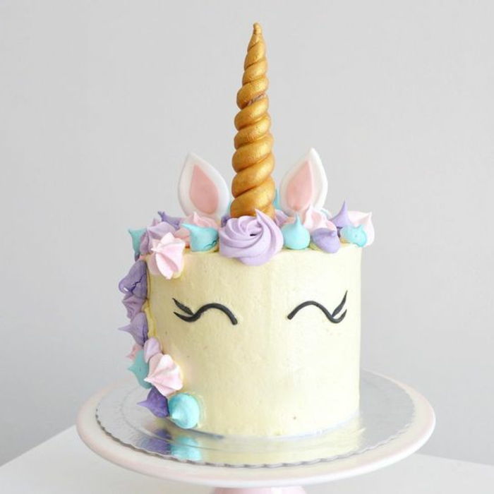 Aqui está um bolo de unicórnio branco com flores roxas