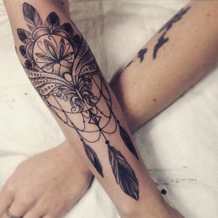 puiki tatuiruotės idėja. Čia yra trys rankos su juoda tatuiruotė su svajonių gaudikliu ir trimis juodomis mažomis plunksnomis