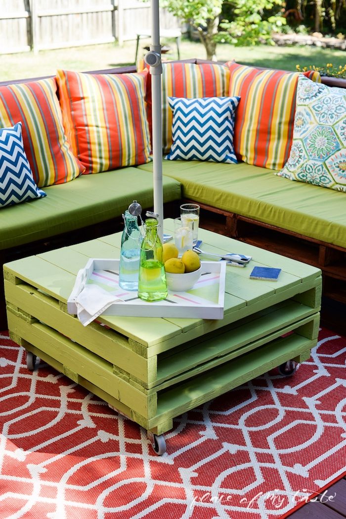Nu laten we u een van onze ideeën zien voor een tafel en een bank met groene en kleurrijke kissem - meubels gemaakt van europallets voor gebruik buitenshuis - tafel, flessen, glazen