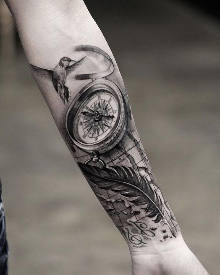 ptak, czarny kompas i długie czarne pióro - pomysł na tatuaż kompasu na dłoni