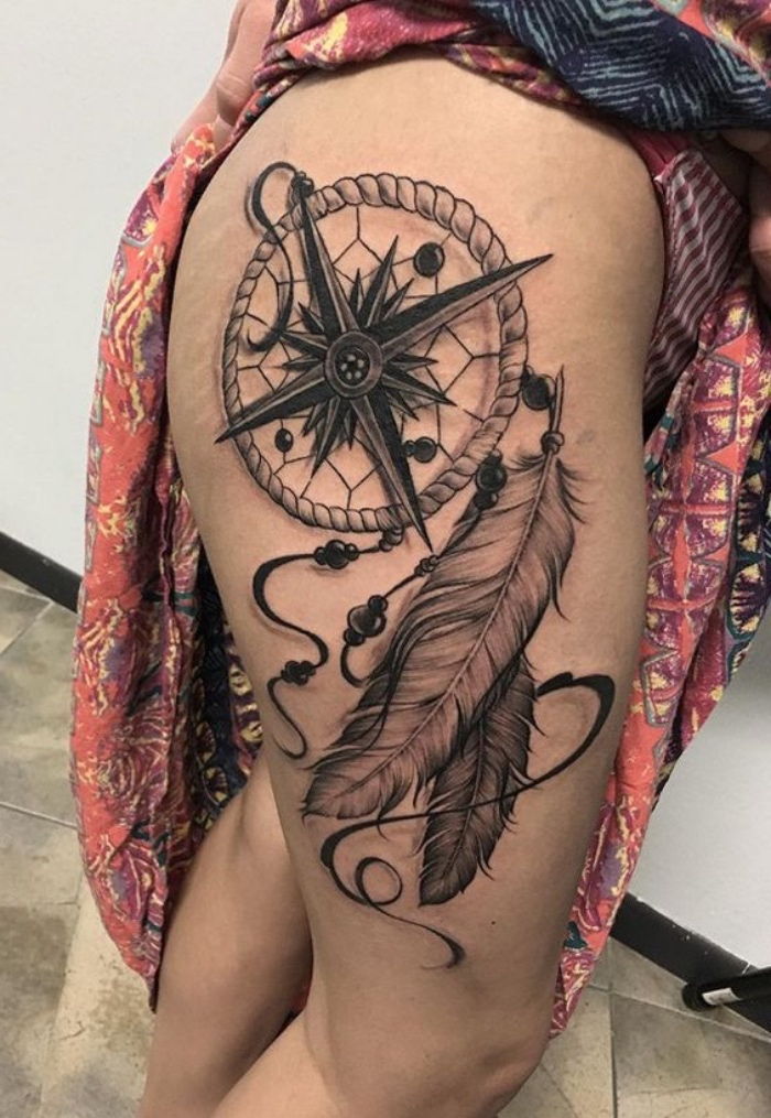Velika tetovaža z velikim črnim kompasom s črnimi puščicami in dvema dolgima belim perjem - ideja za tetovažo za žensko