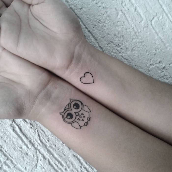 Iată două tatuaje mini negre cu o bufniță și o inimă mică pe încheietura mâinii