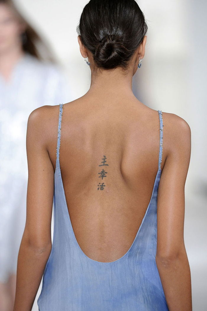 idei tatuaj cool pentru femei, hieroglif pe spate, decolteu scăzut, aspect vară