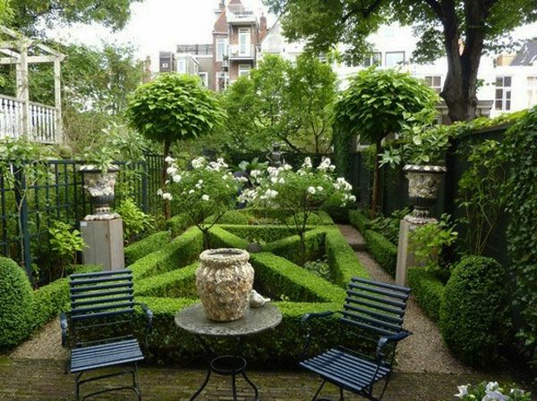 zielony ogród z dwoma czarnymi krzesłami i wieloma zielonymi roślinami