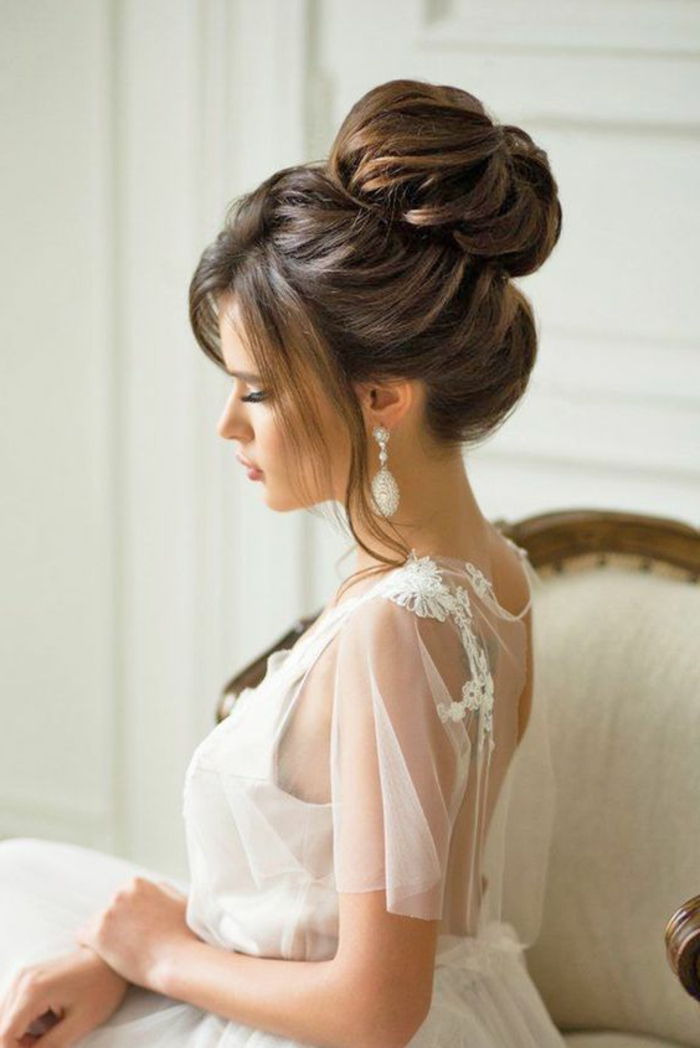 brud med vit klänning med dekorationer och elegant dut frisyr