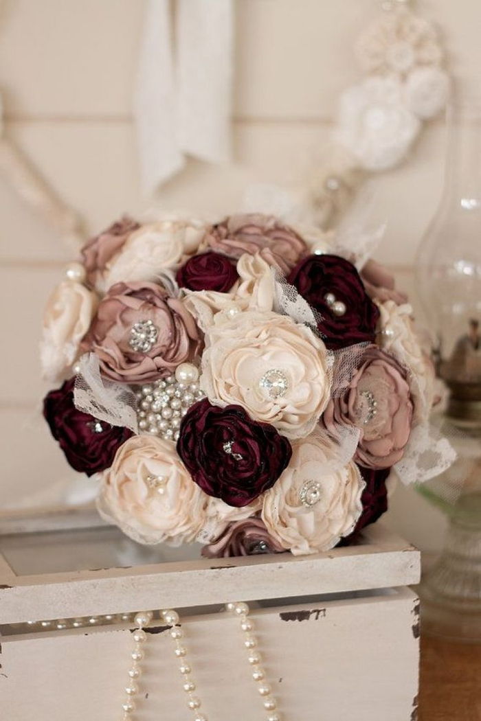 sydda blommor dekorerade med glaspärlor i röda, vita och krämiga färgbröllopbuketter