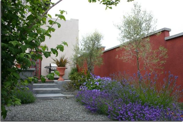 hoge omheining mediterrane tuin grind en rode kleur