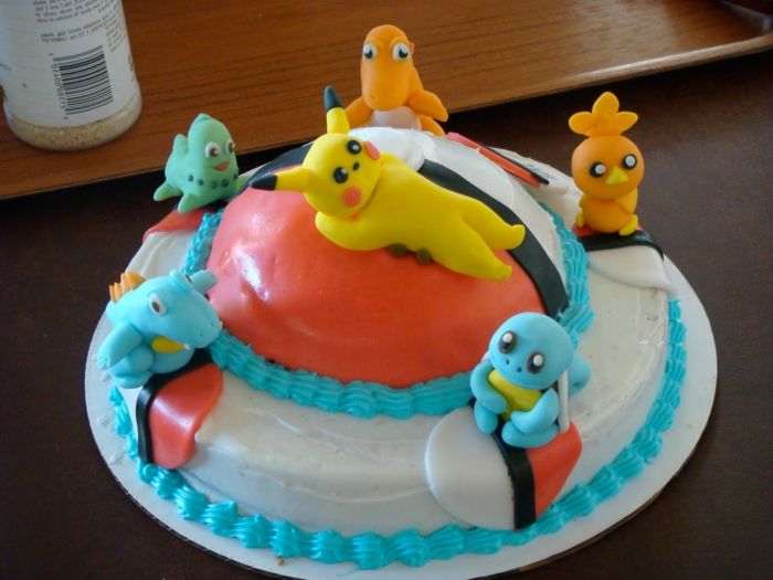 una pokeball rossa e sei piccoli esseri pokemon, un pikachu - un'idea per una torta pokemon con una crema blu