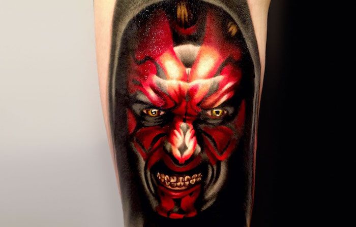 o mână care deține un tatuaj mare cu un monstru roșu cu războaie cu ochi galbeni - idei de tatuaje de război stele
