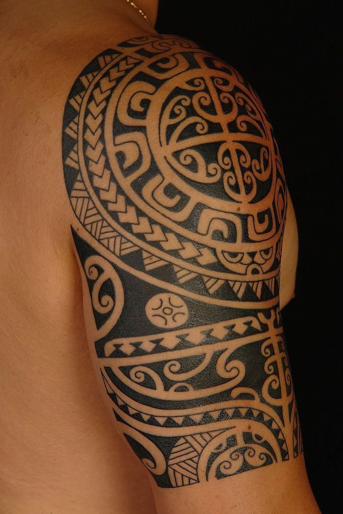 un uomo con una mano che tiene un grande tatuaggio nero maori con molti motivi di tatuaggio maori neri