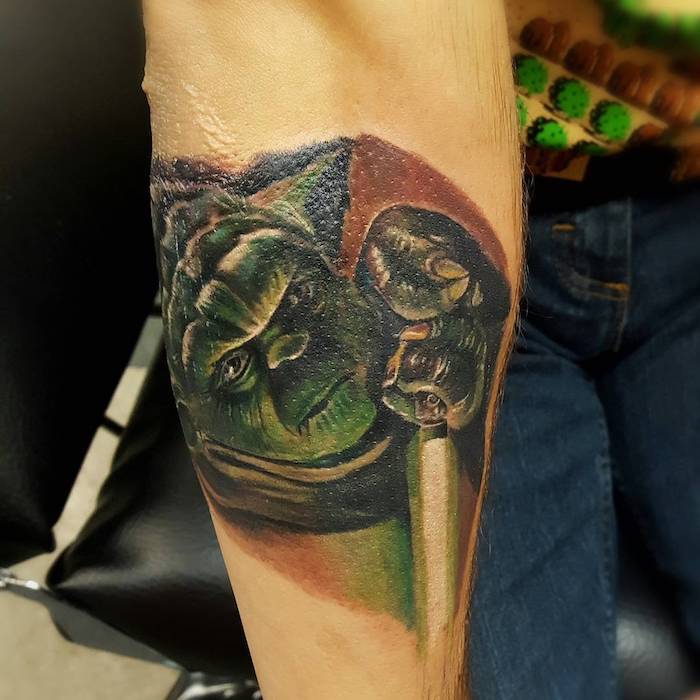 o mână cu un mic verde Jedi - joda cu sabia sa verde